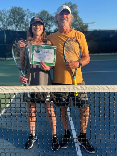 Two tennis players with racquets and award